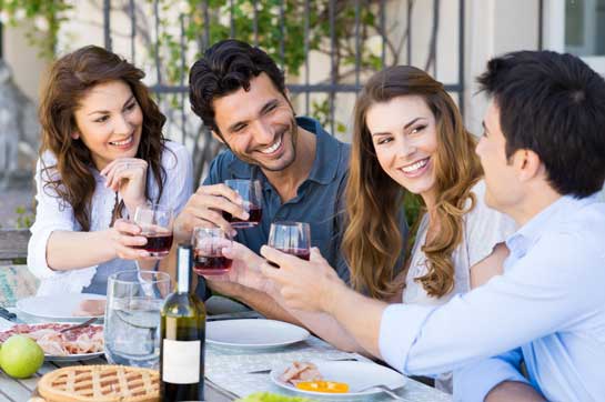 Two young couples toasting each other at picnic table