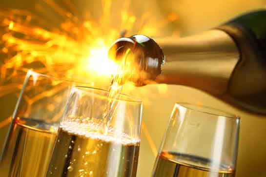 Champagne being poured in glasses against sparkling lightburst 