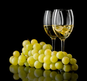 Two glasses of chardonnay next to large bunch of chardonnay grapes