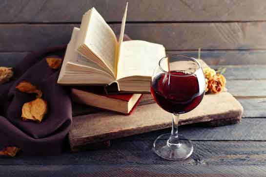 glass of red wine, open book, dried roses